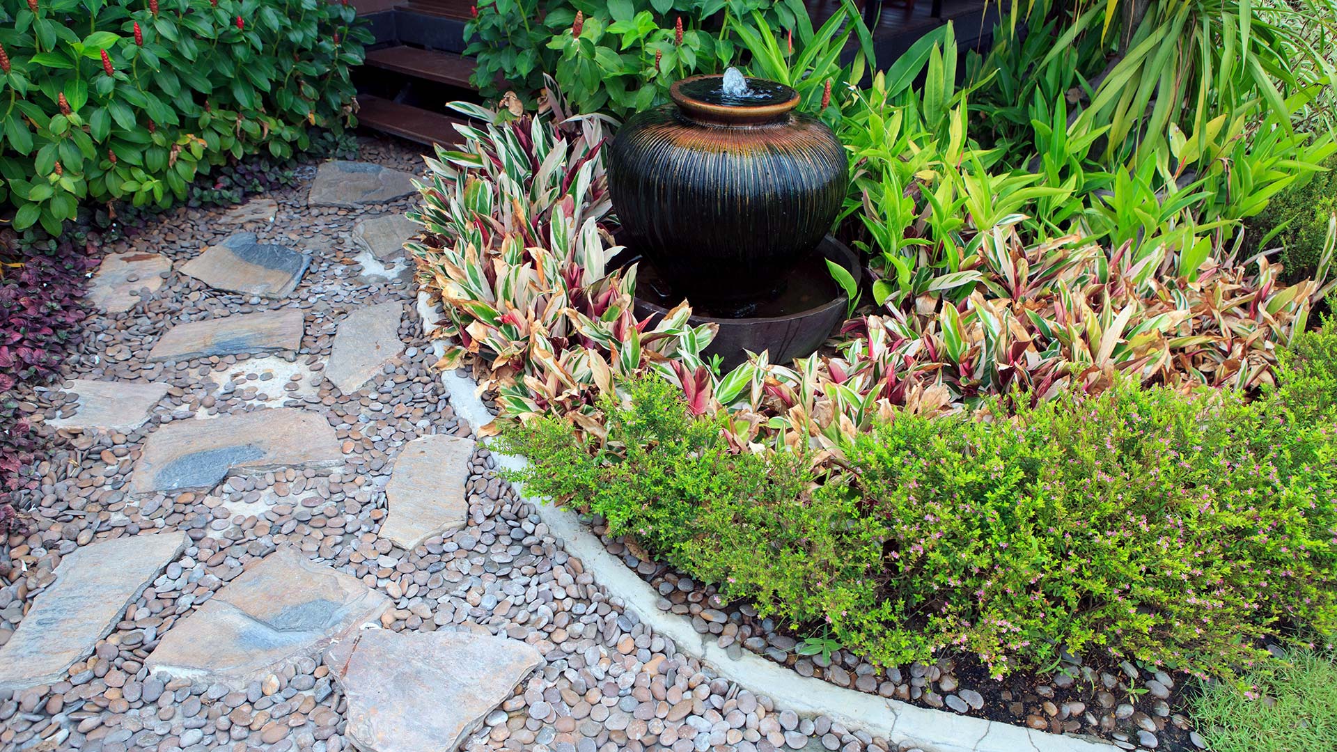 Home landscaping bed with plantings and a water feature in Milwaukie, OR.