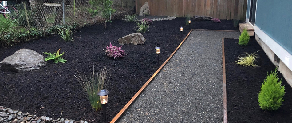 Mulch in landscape bed with plantings and outdoor lighting in Damascus, OR.